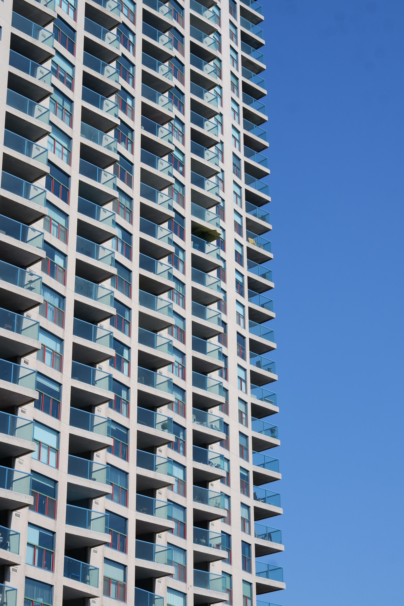 Facciata di un condominio contemporaneo con balconi bianchi e parapetti in vetro azzurro
